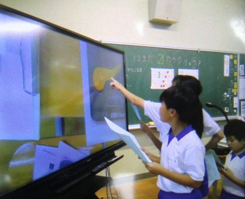 自動販売機にある点字を一覧表を見ながら読んでいる様子