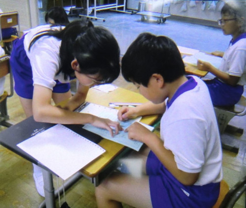 点字名刺をクラスメイトと一緒に読んでいる様子